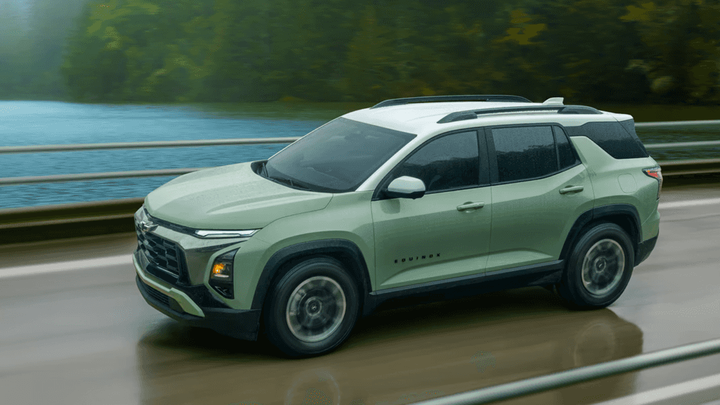 2026 Chevrolet Equinox SUV in light green driving on a wet road near a lake and forest, showcasing its modern design and two-tone roof.