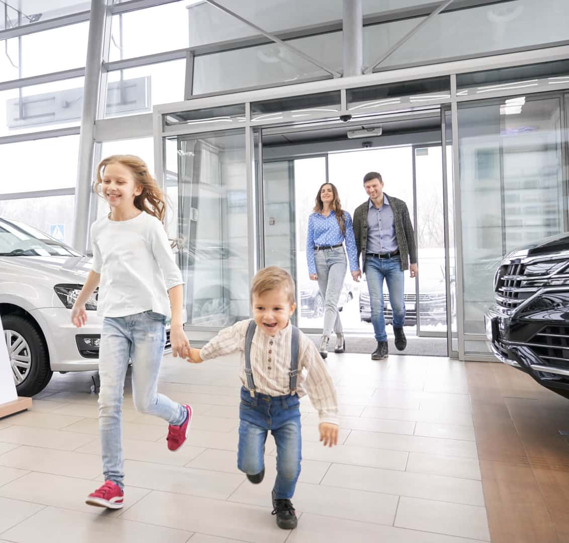 Parents walking into a dealership with two children