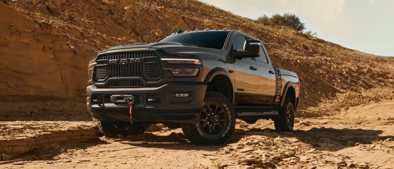Low front three-quarter view of a grey RAM 2500 on a rocky desert trail.