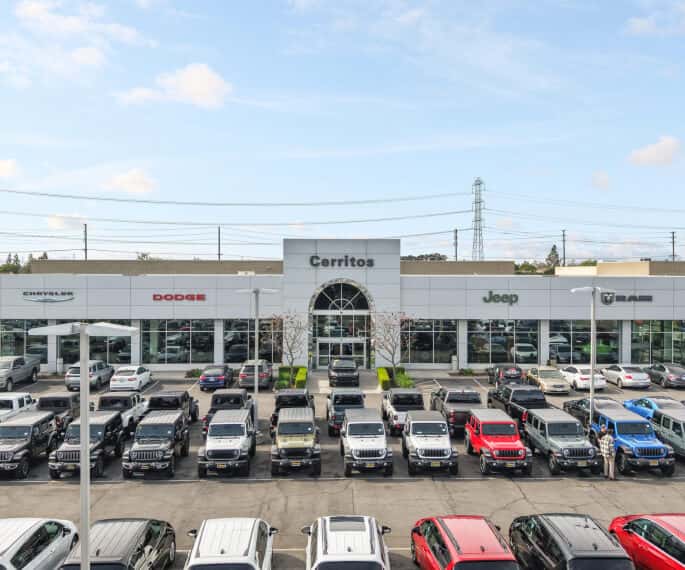High-angle view of the Cerritos CDJR dealership building with new vehicles parked on the lot.
