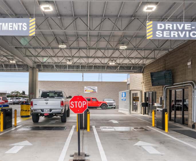 Covered drive-in service bay at Cerritos CDJR dealership featuring a silver RAM truck and stop sign.