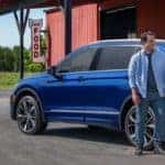 A couple standing in front of a 2022 Volkswagen Tiguan at a country store