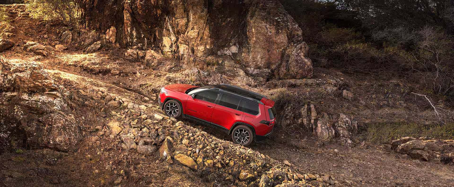 Red 2026 Jeep Cherokee driving up rocky road