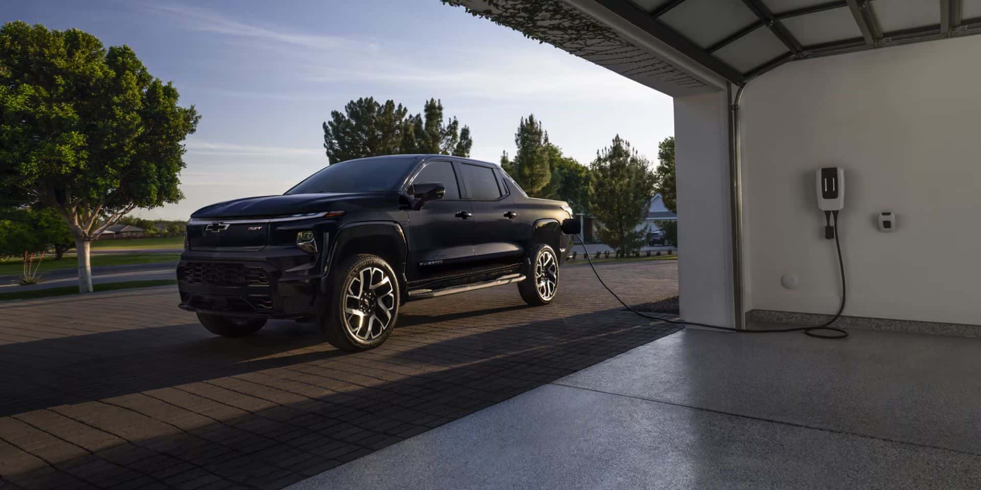 2025 silverado ev parked next to a garage charging 