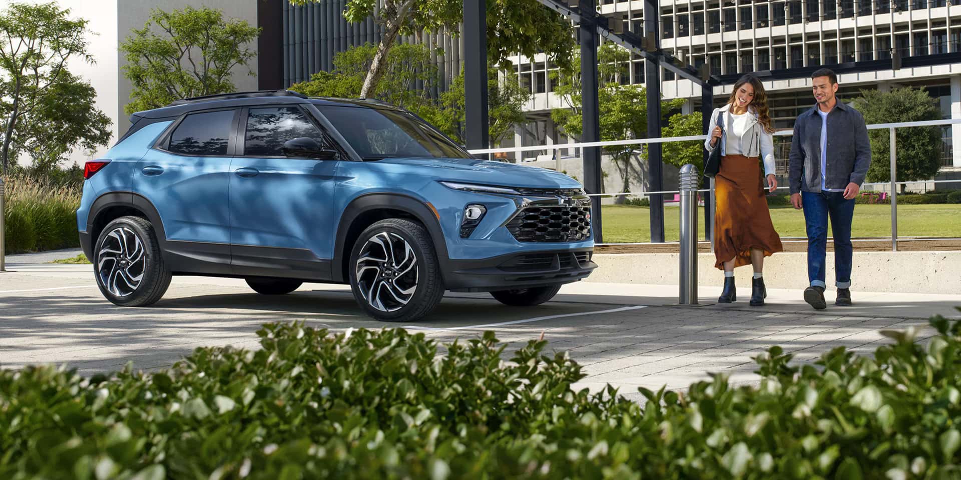 a blue 2026 chevy trailblazer parked next to a building with people walking up to it. 