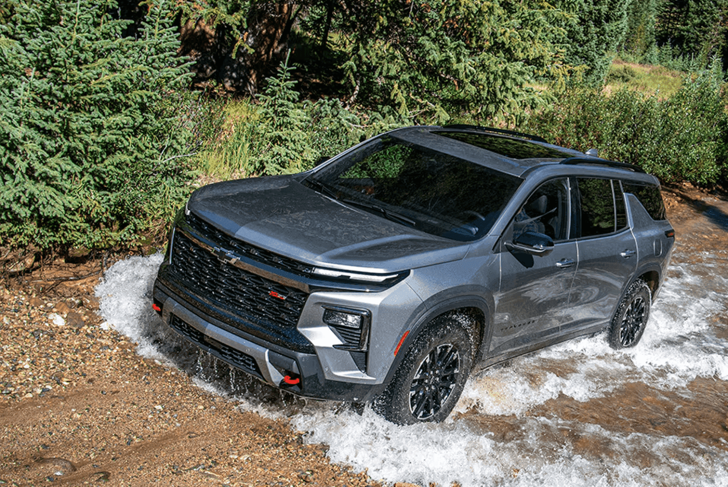silver 2026 chevrolet traverse driving through rugged road and water