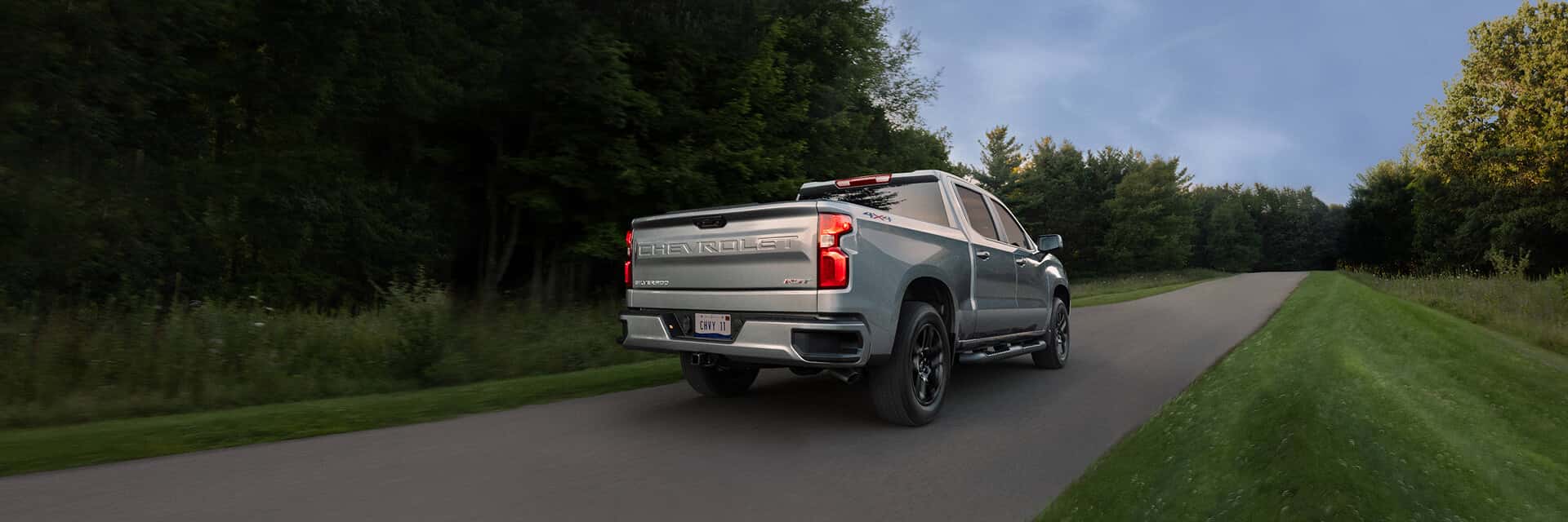 silver chevrolet silverado driving on a road towards dark clouds