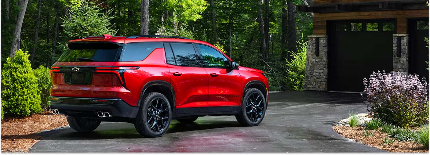 Rear three-quarter view of a red 2026 Chevrolet Traverse parked in a residential driveway.