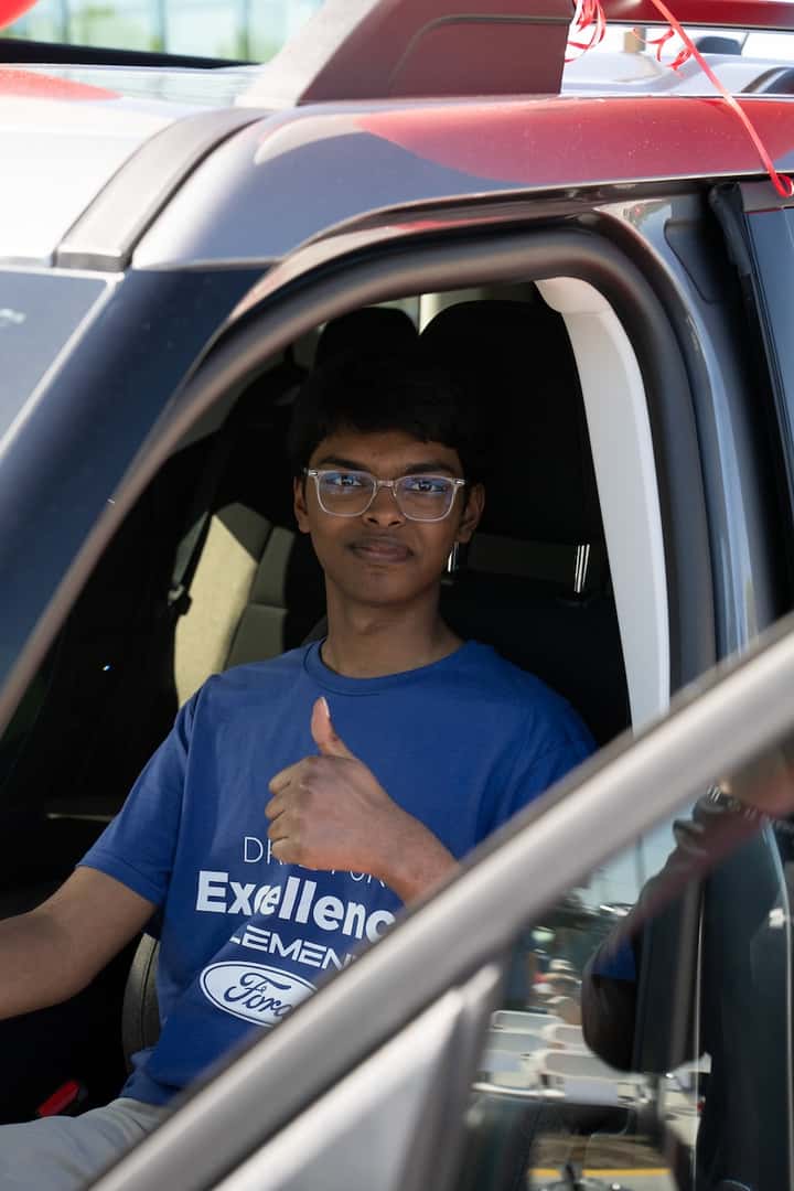 Teen male sitting in drivers seat with a thumbs up