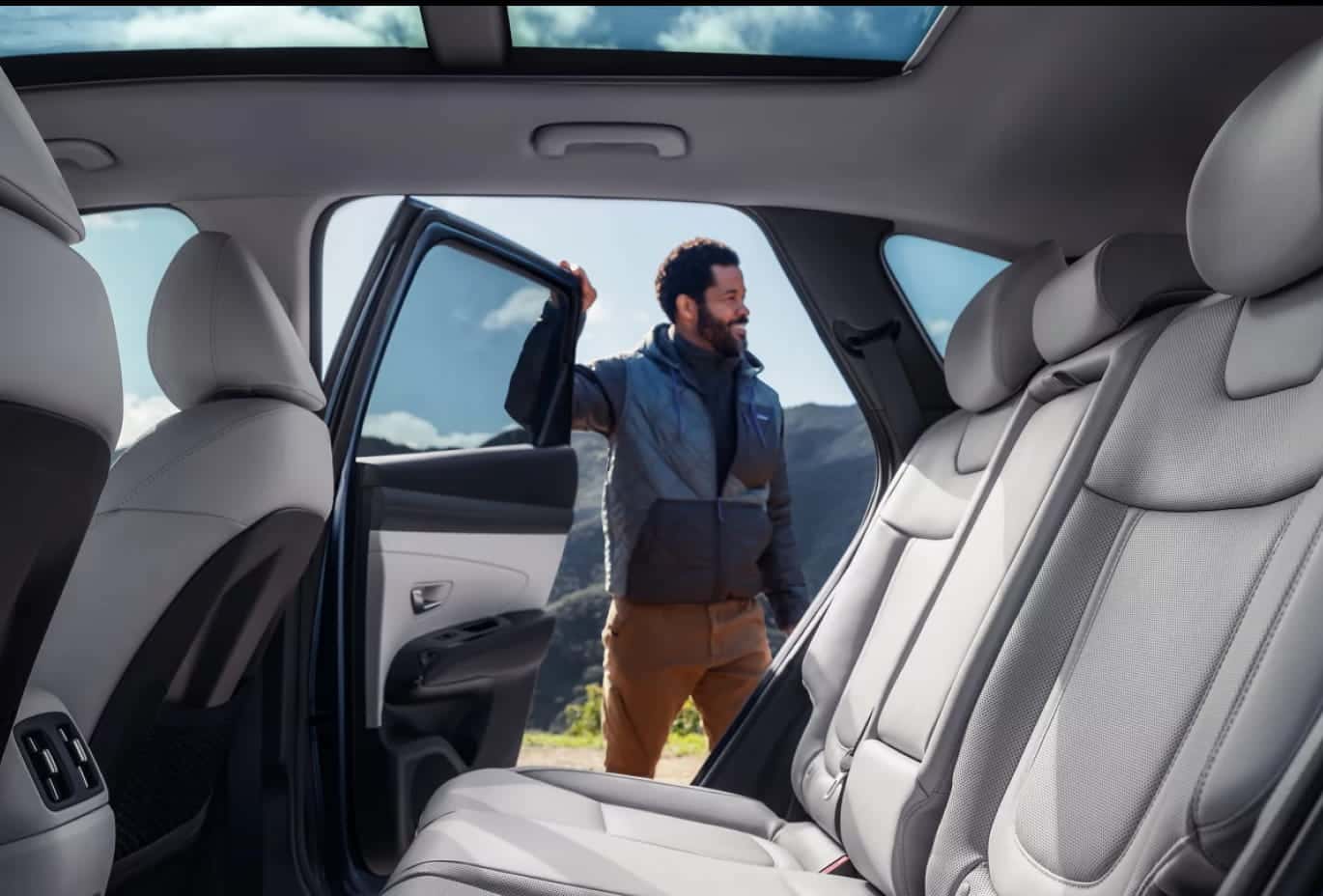 Hyundai Tucson interior featuring spacious rear seating and a panoramic sunroof with the rear passenger door open.