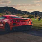 2026 Chevy Corvette Stingray parked on the side of the road with people playing golf in the background
