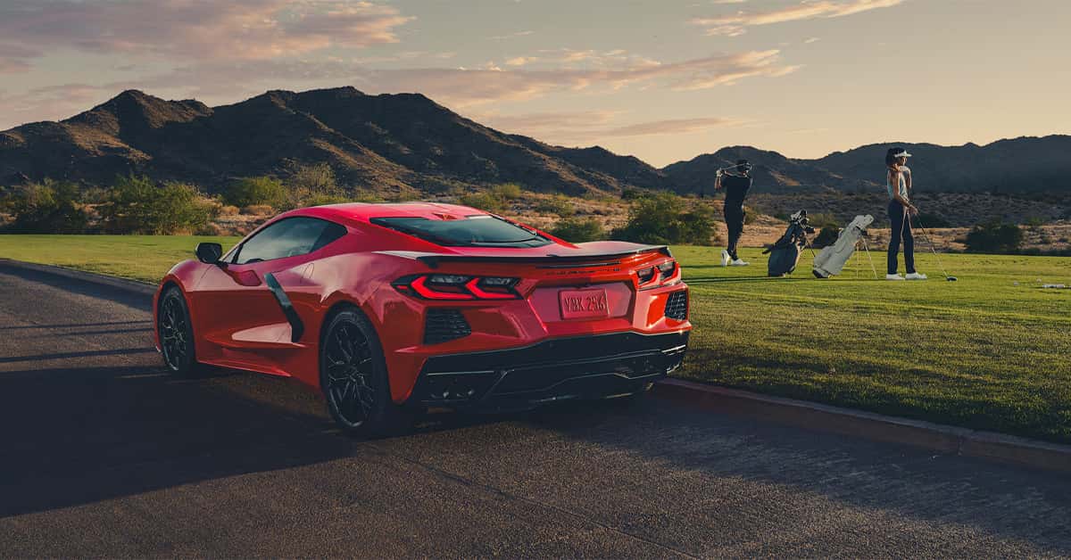 2026 Chevy Corvette Stingray parked on the side of the road with people playing golf in the background