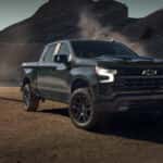 Black Chevrolet Silverado 1500 Z71 pickup truck parked in a rugged desert landscape with rocky mountains in the background.