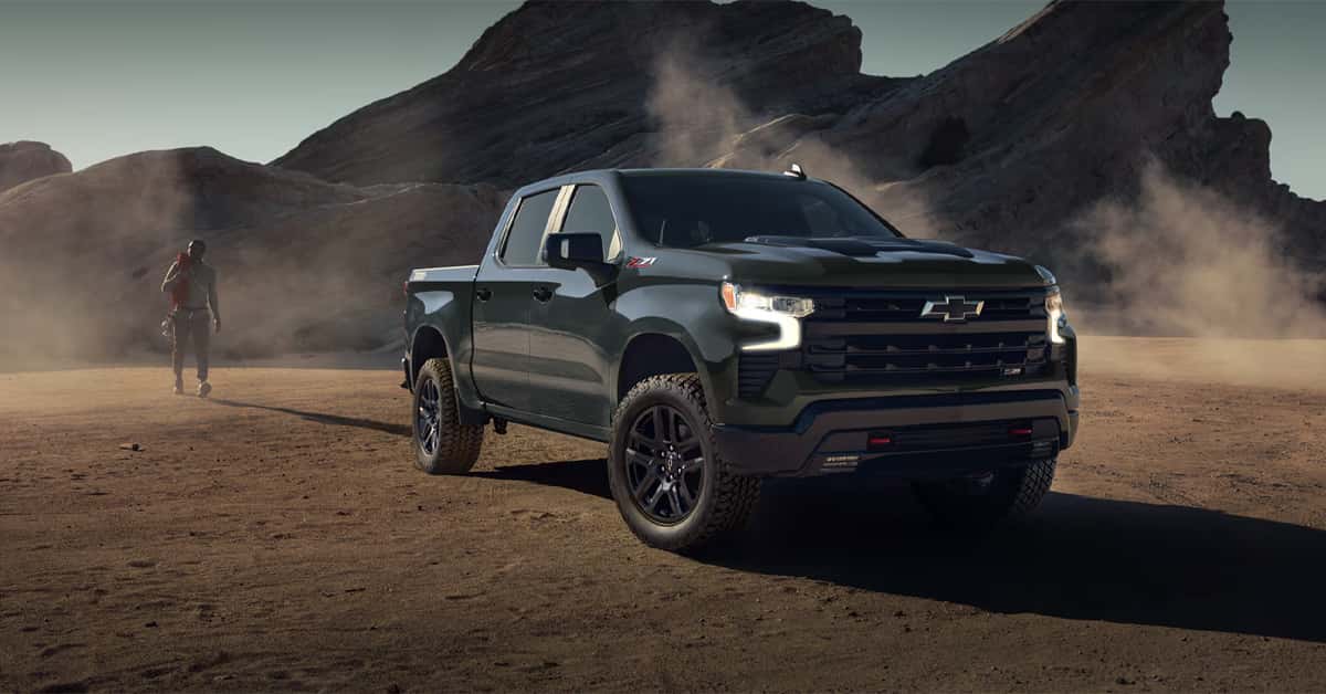 Black Chevrolet Silverado 1500 Z71 pickup truck parked in a rugged desert landscape with rocky mountains in the background.