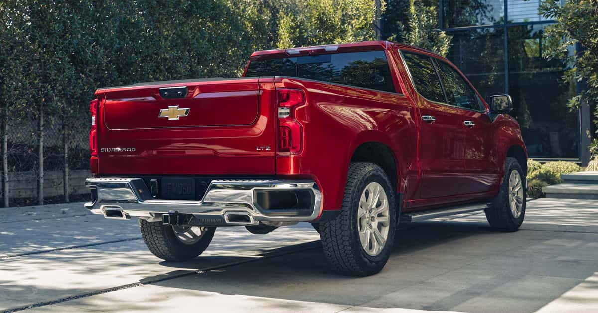 Red Chevrolet Silverado 1500 pickup truck parked outdoors on a paved driveway, viewed from the rear three-quarter angle.