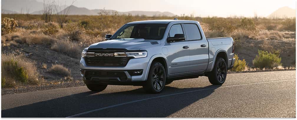 Silver 2026 RAM 1500 pickup truck parked on a paved desert road.