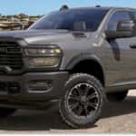 Front three-quarter view of a dark grey 2026 RAM 2500 pickup truck on a desert dirt road.