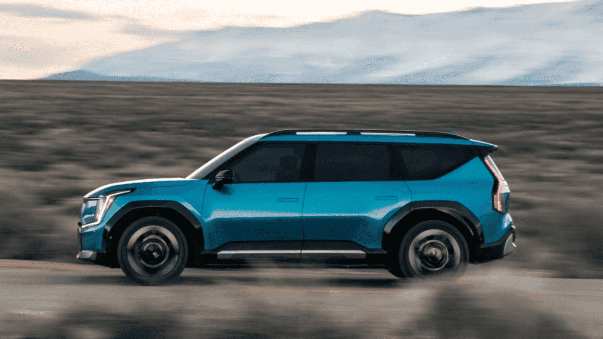Side profile of the 2024 Kia EV9 driving on a dirt road