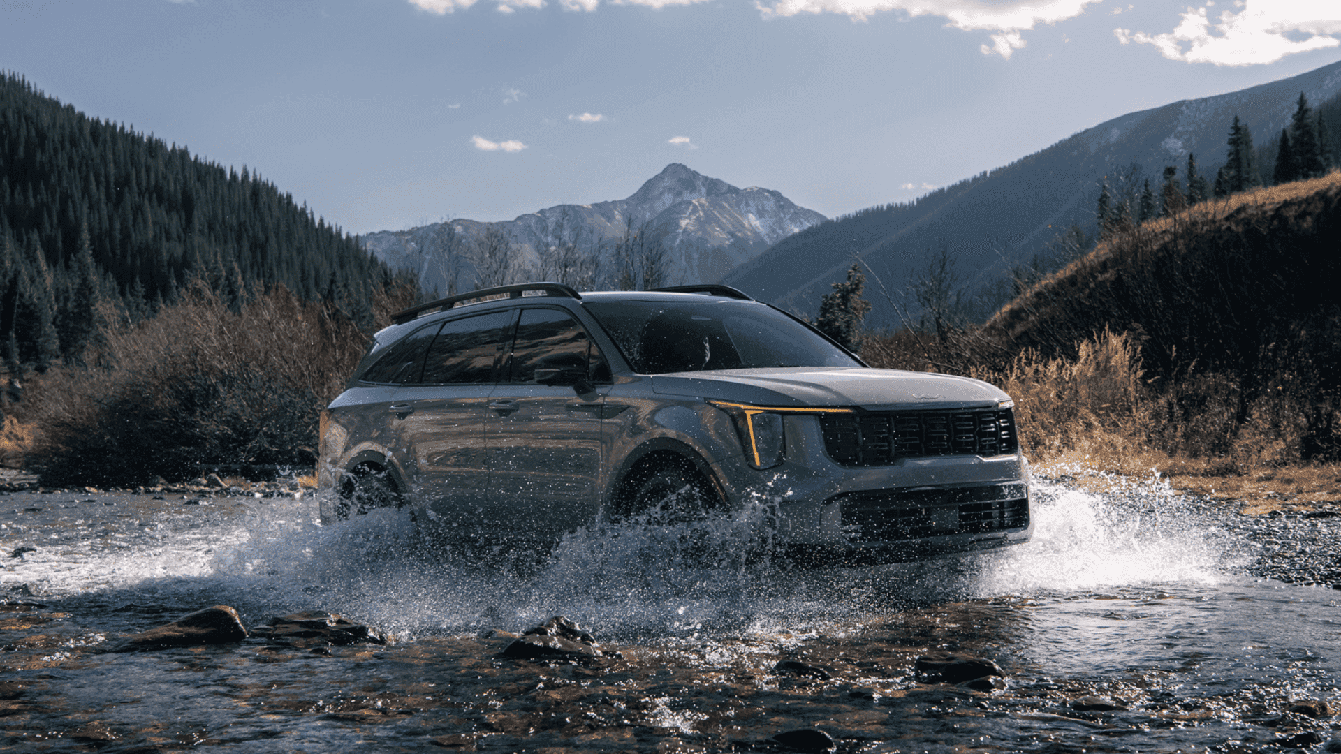2024 Kia Sorento crossing a shallow river with mountains and trees behind