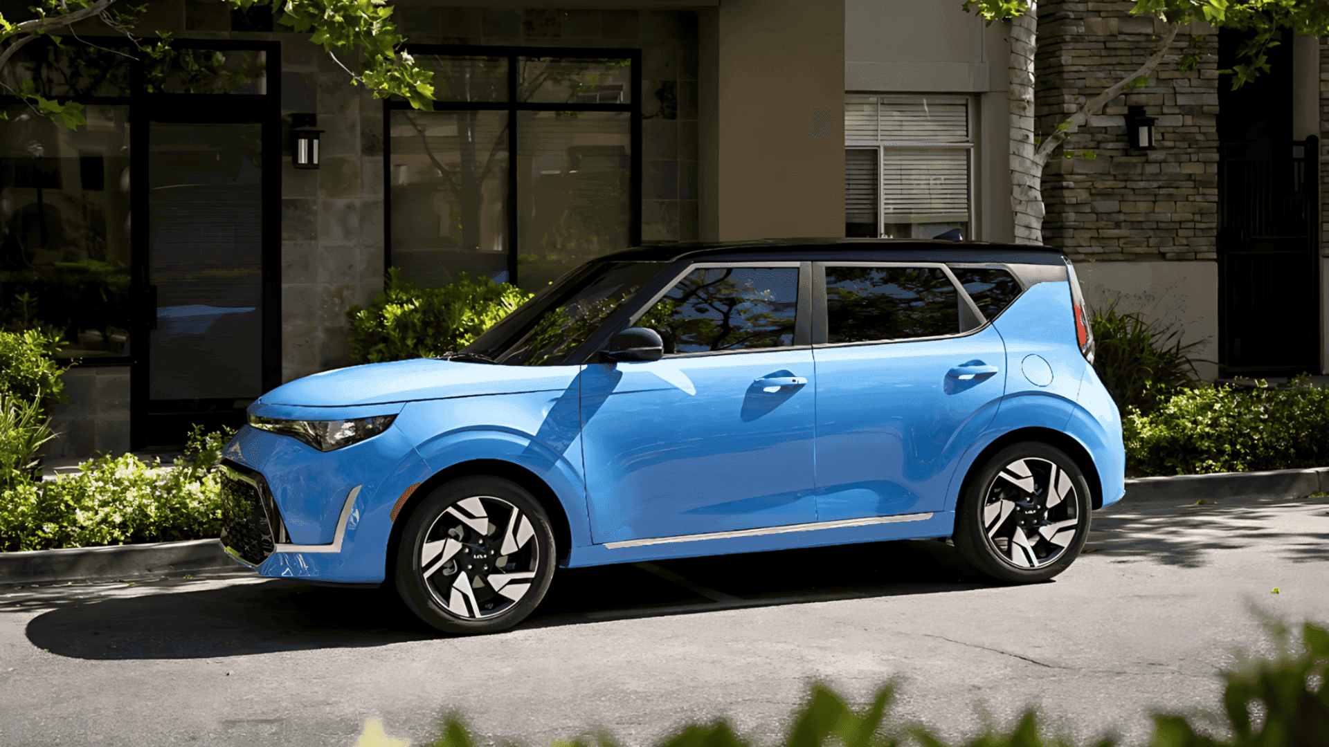 Bright blue 2024 Kia Soul parked in a shaded residential area with greenery