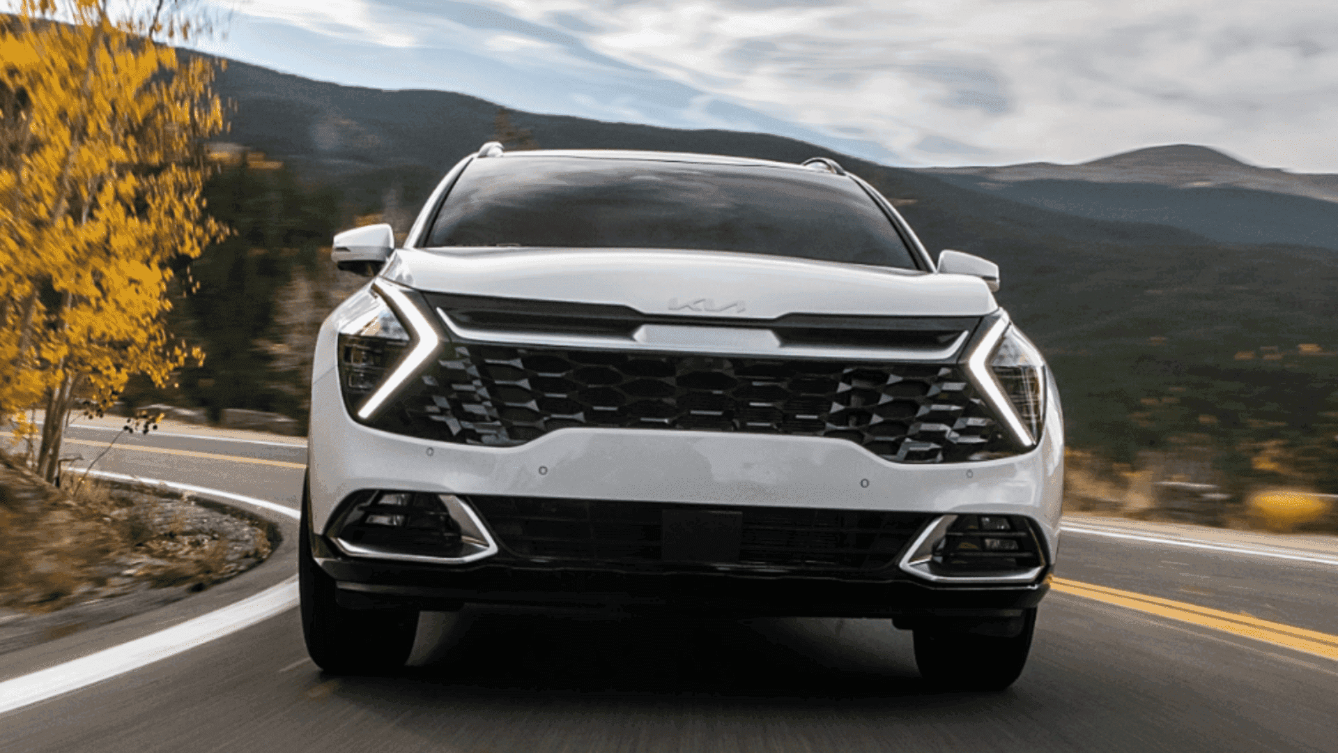 Front view of white Kia Sportage driving on a curvy road