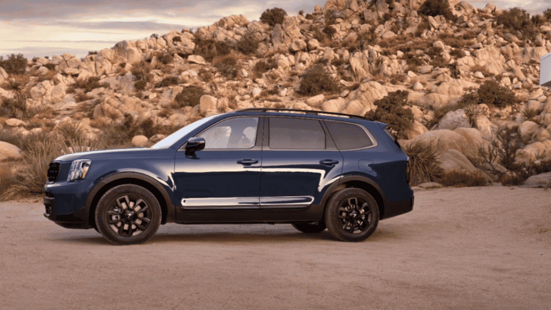 Side view of a blue 2024 Kia Telluride parked near desert rock formations