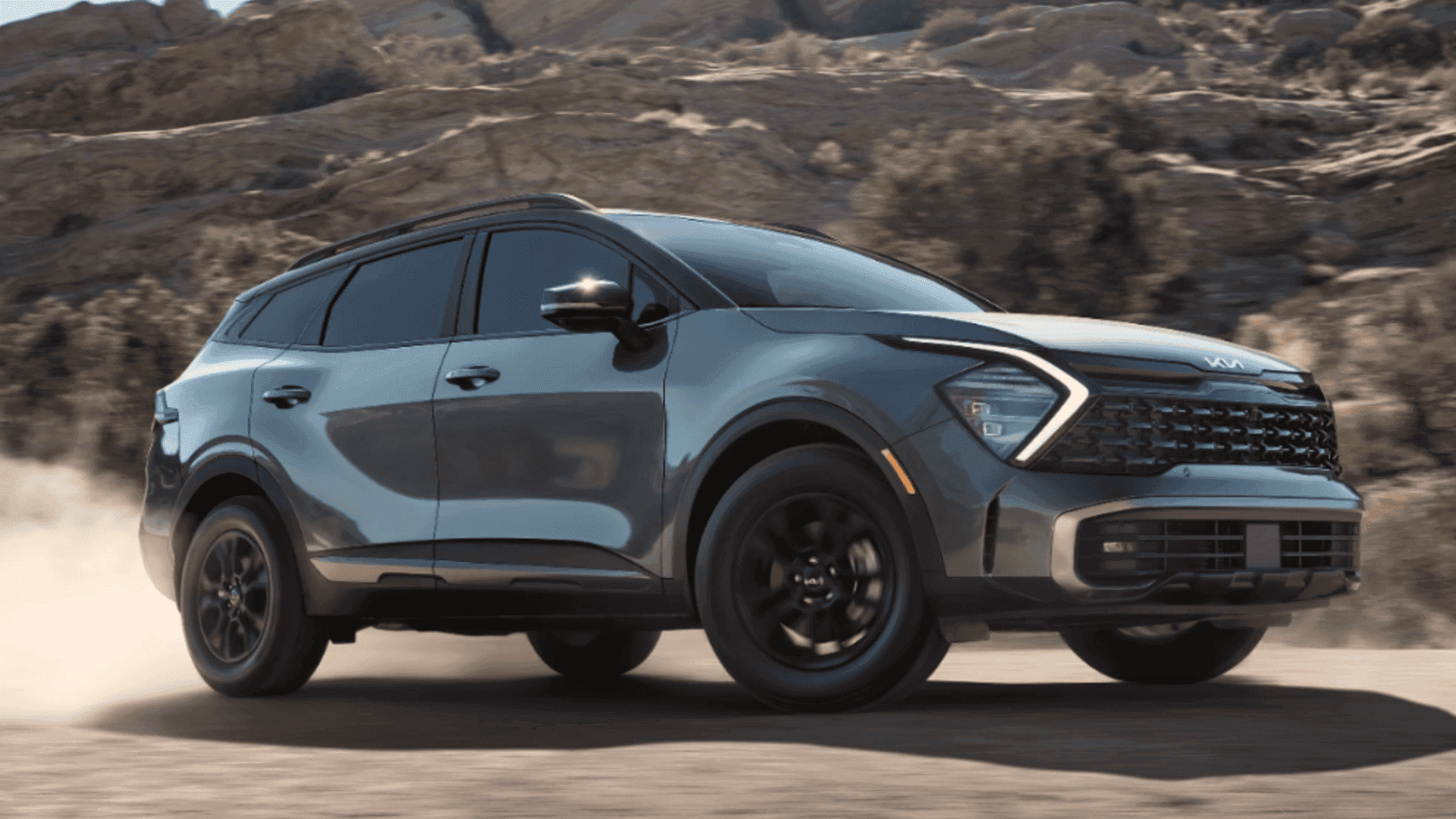 Gray 2024 Kia Sportage SUV kicking up dust while driving off-road