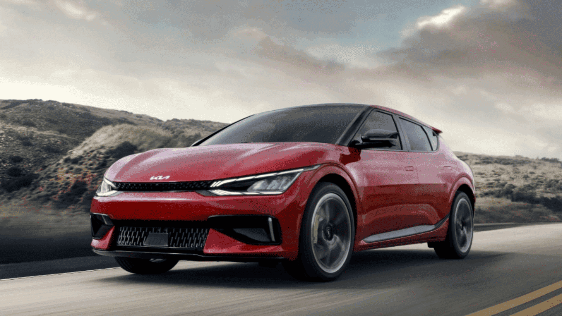 Red 2024 Kia EV6 driving on a scenic mountain road