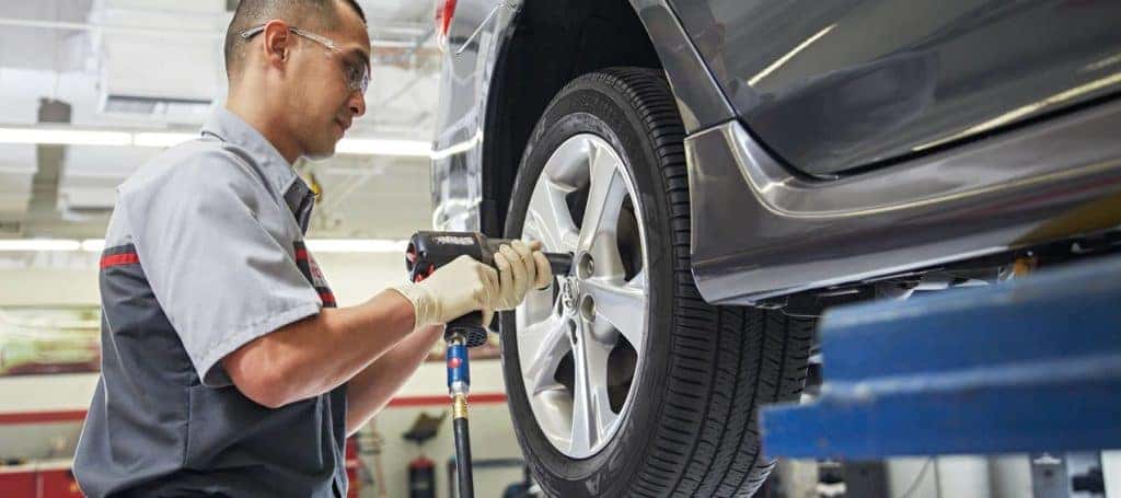 Toyota service technician unscrewing a Tire's lug nuts