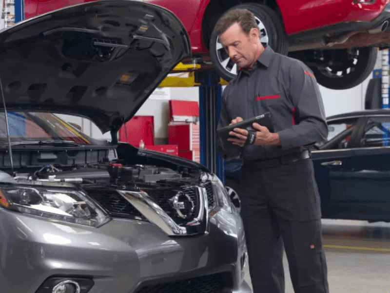 Nissan service technician inspecting vehicle