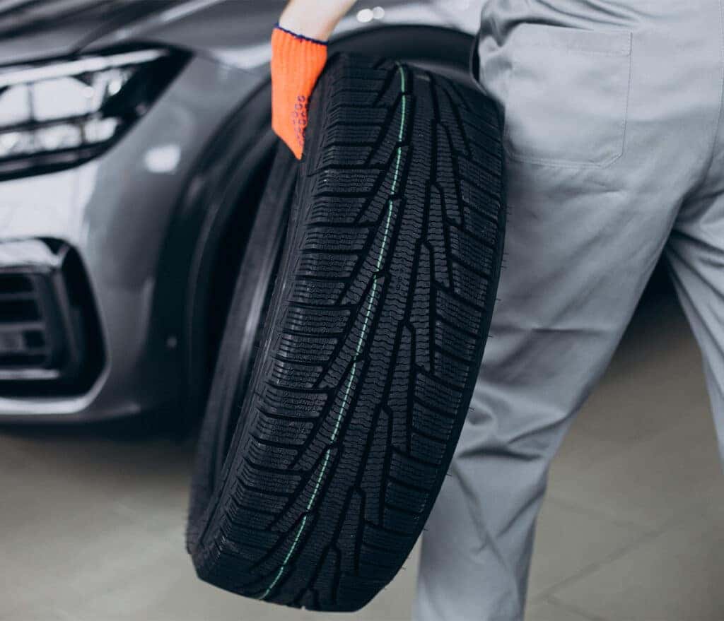 How to check your tires' health at Delaney Chevrolet of Indiana | Mechanic carrying brand new tire with markings on it