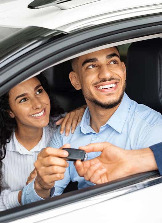 Leasing versus Buying a Hyundai at Delaney Hyundai of Indiana in Indiana, PA | Salesman handing over new car keys to clients sitting in the front seats