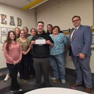 Den Kelly representative holding check to gift to PTO members