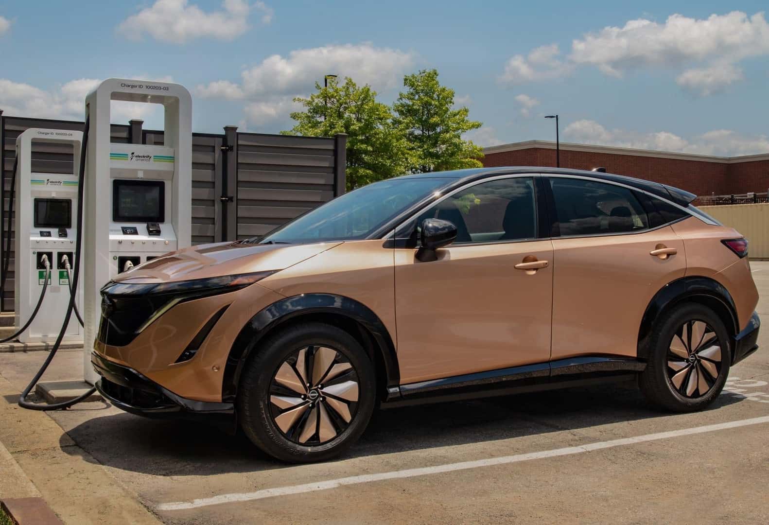 The Rose Gold 2024 Ariya, Parked At A Charging Station, With Elegance 