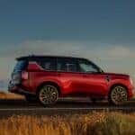 The Sexy Red Side Profile Of The 2025 Nissan Armada, Driving Past Golden Grass