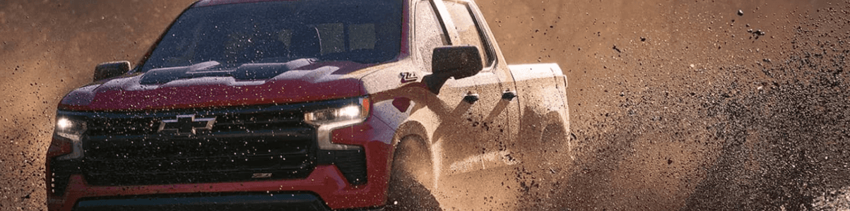 a red 2024 Chevrolet Silverado driving through mud