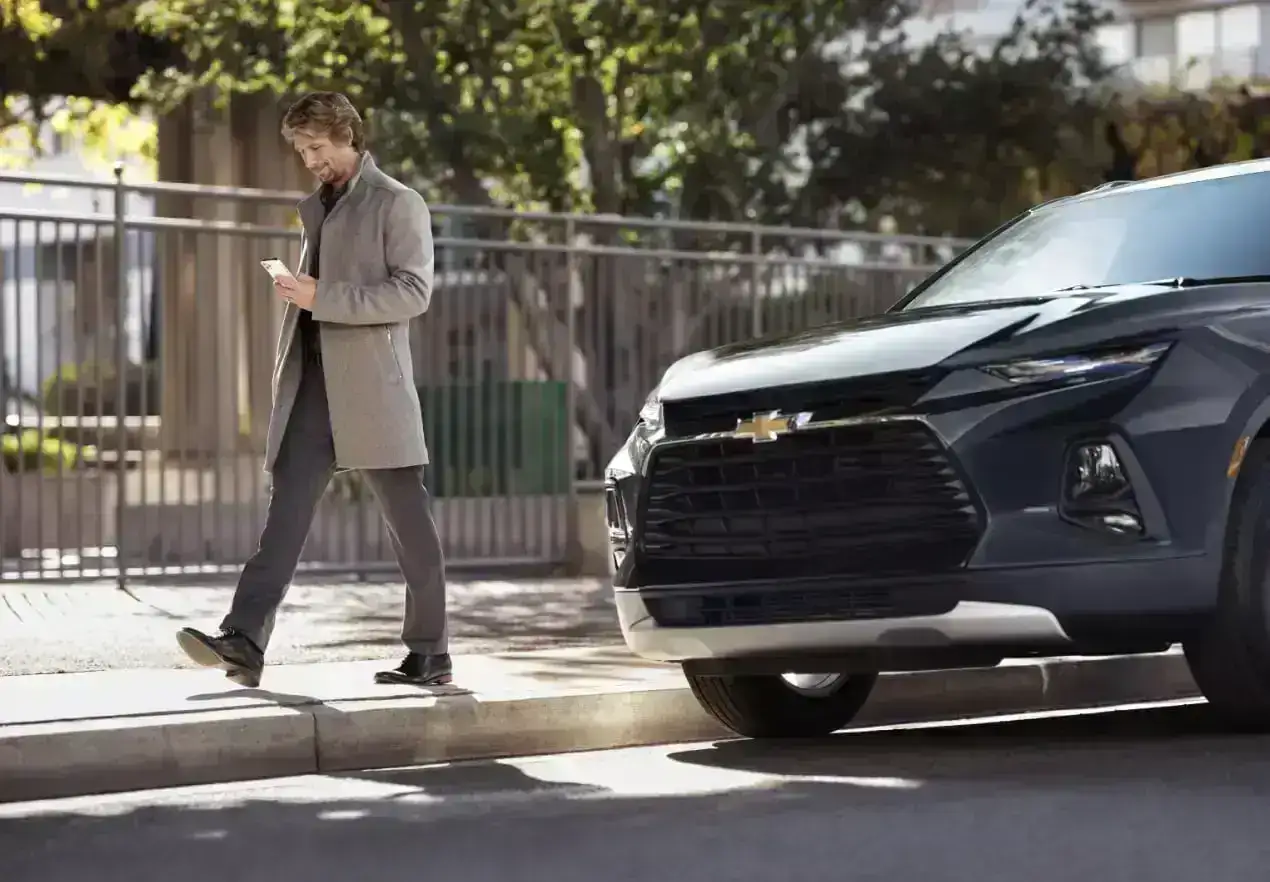 man with phone walks by Chevy SUV parked