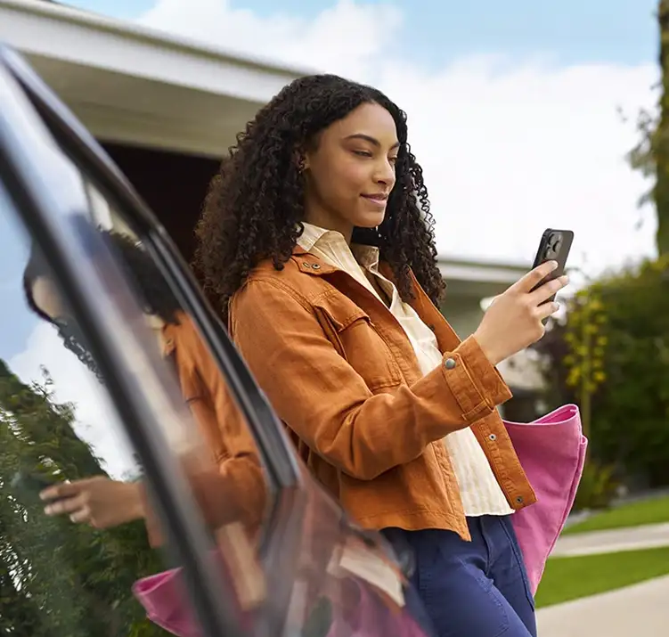 Woman standing beside an open Chevrolet Equinox door using her phone