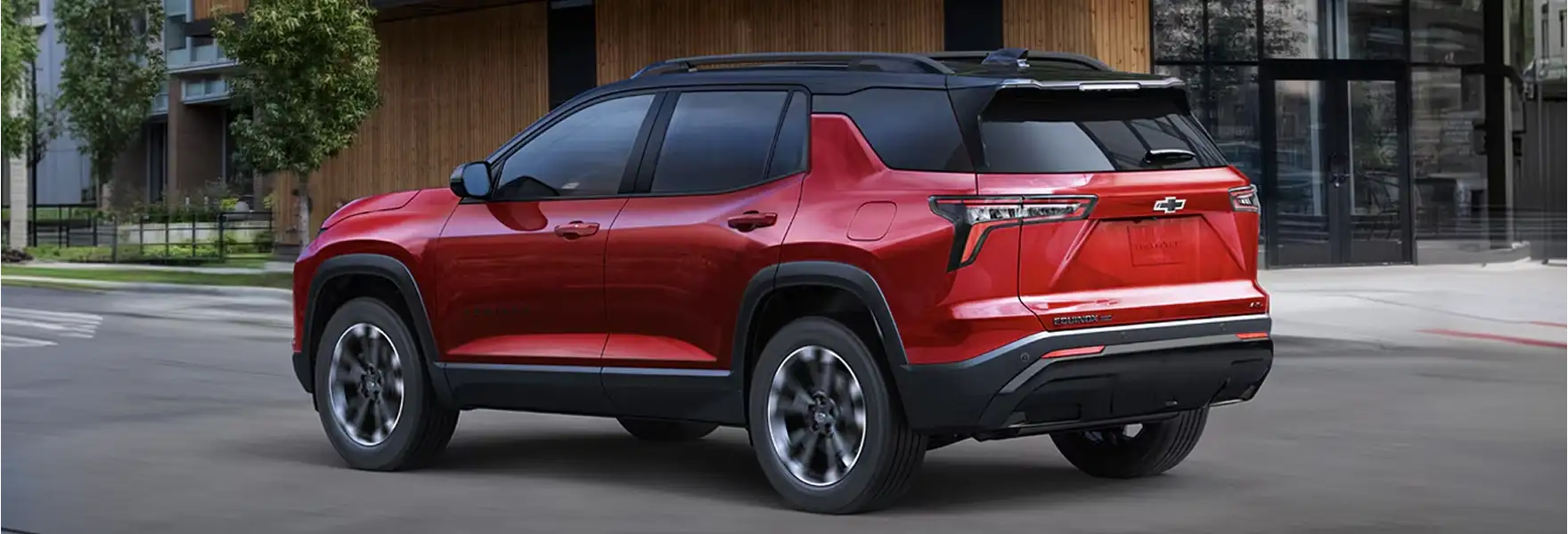 Red 2027 Chevrolet Equinox rear three-quarter view parked beside a modern building