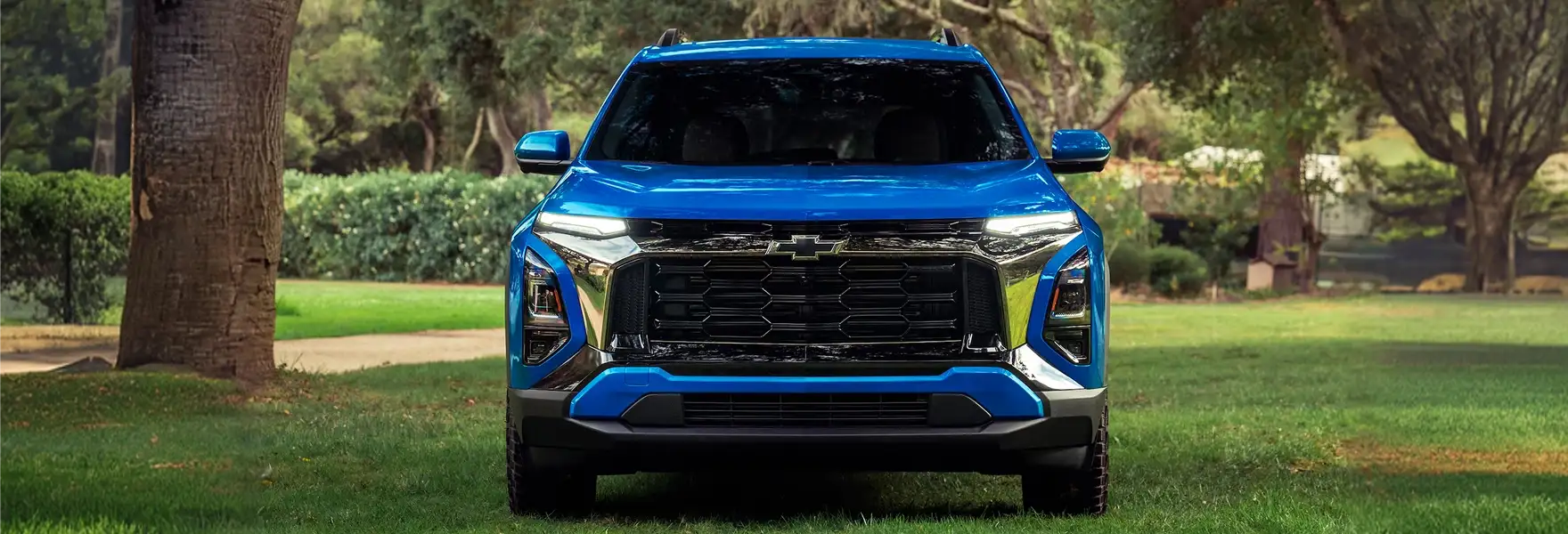 Blue 2027 Chevrolet Equinox front view parked on grass among trees