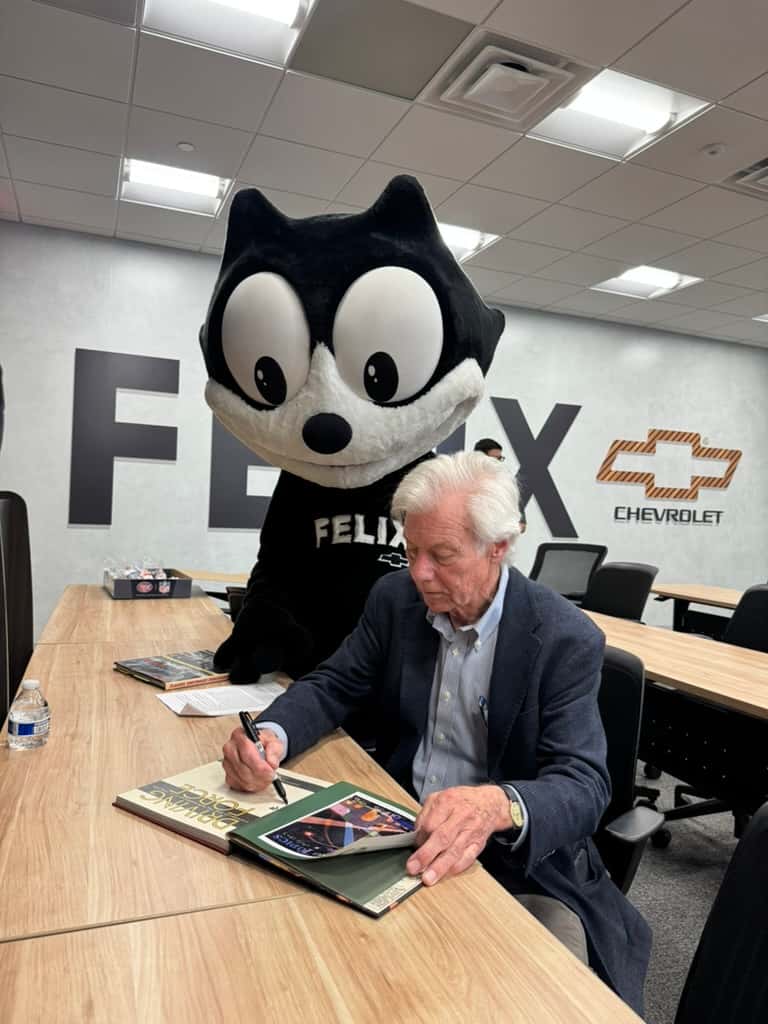 Former Felix Chevrolet owner Darryl Holter signing a book with Felix the Cat at Felix Chevrolet