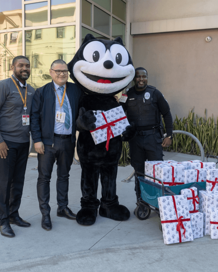 Felix the Cat delivering wrapped gifts during a Felix Chevrolet community outreach event in Los Angeles