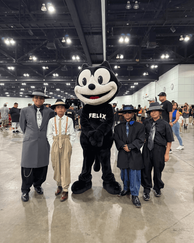 Felix the Cat posing with young car show attendees at a Los Angeles community event