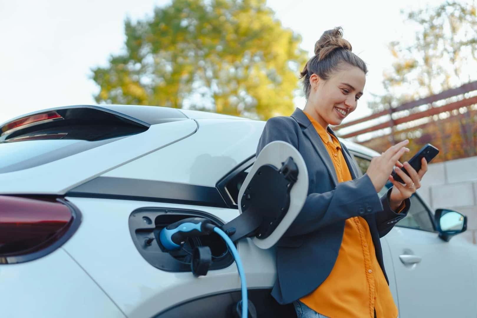 Woman charging electric vehicle at charging station