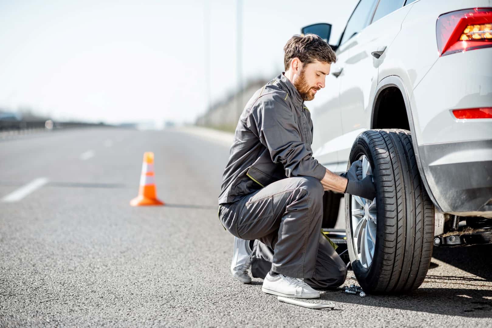 Man changing tire on side of road