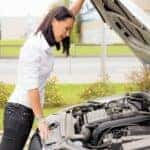 Woman looking under the hood of her broken car