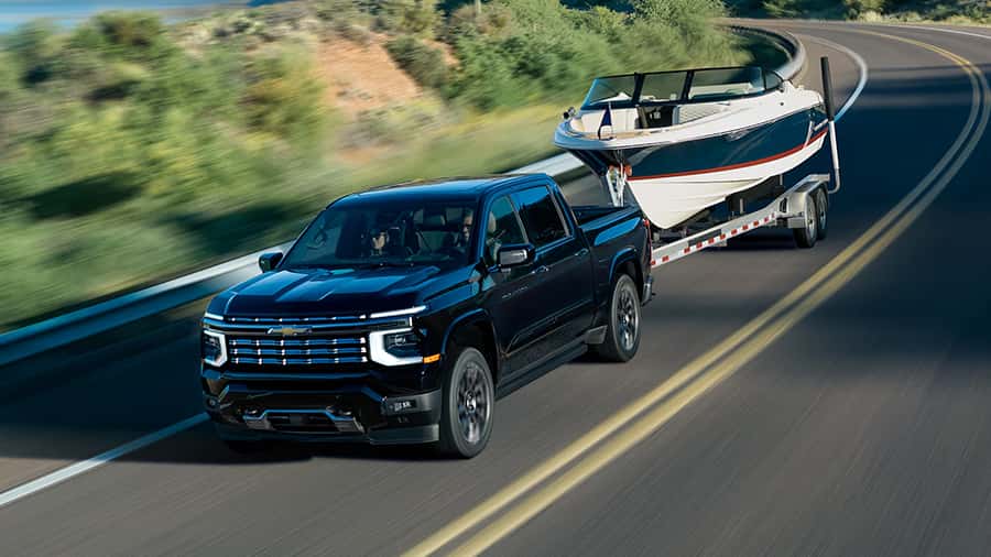2027 Silverado Driving Down A Road Towing A Boat