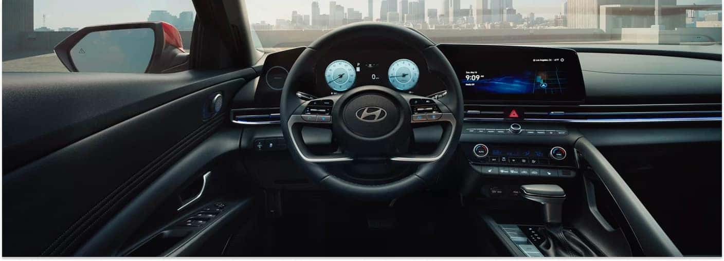 The modern driver's cockpit of a 2026 Hyundai Elantra features a digital instrument cluster, a large central infotainment touchscreen, and a multi-function steering wheel set against a city skyline backdrop.