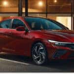 Red 2026 Hyundai Elantra sedan parked on a city street, shown from a front three-quarter view.