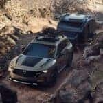 2025 Mazda CX-50 towing a car while driving through rocky terrain
